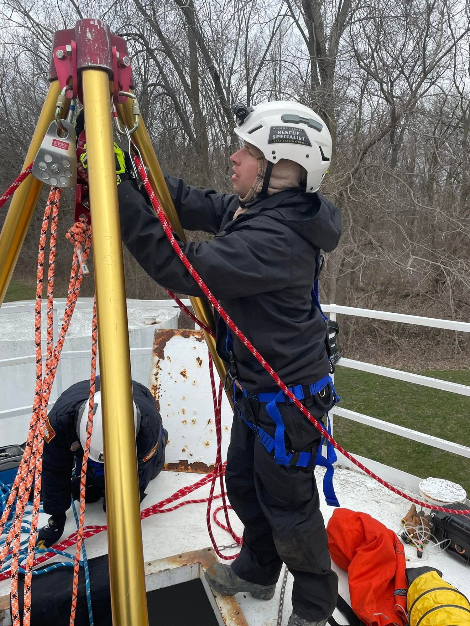A rescuer rigging a tripod and rope system during confined space training