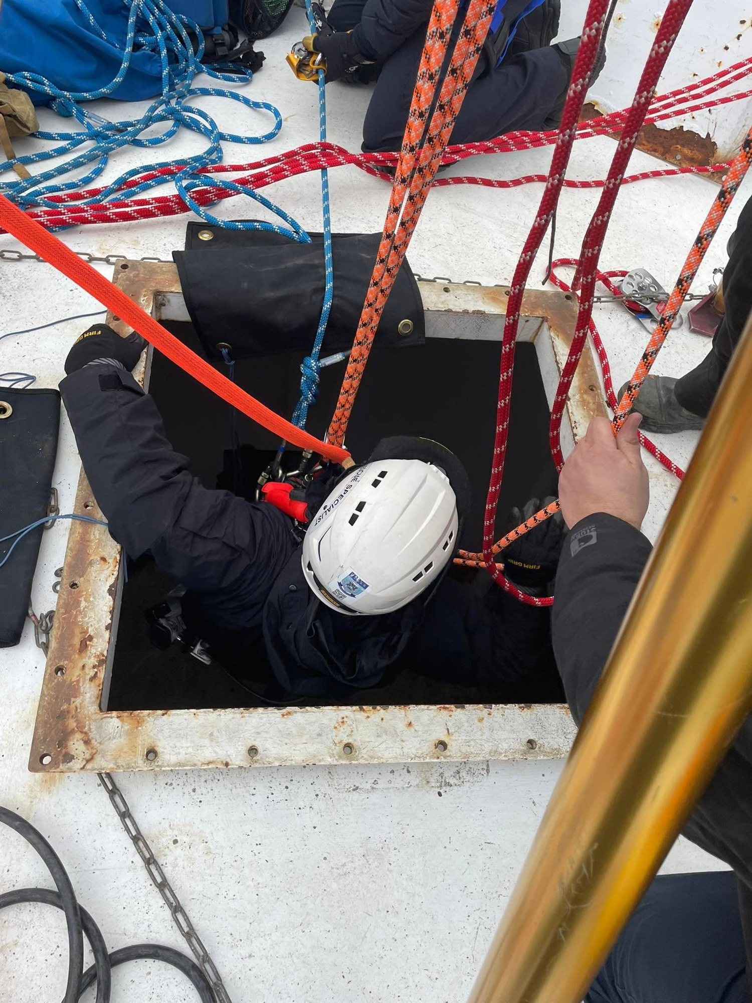 A rescuer lowered into a confined space during training