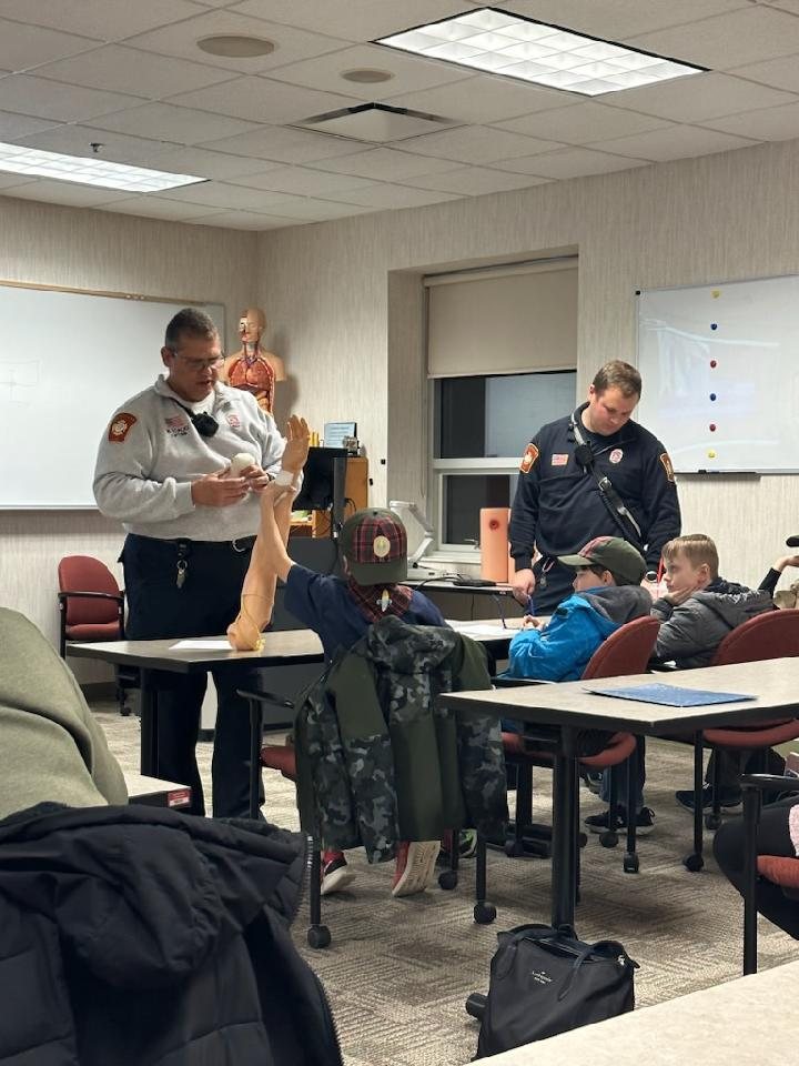A firefighter instructor demonstrating CPR to a class