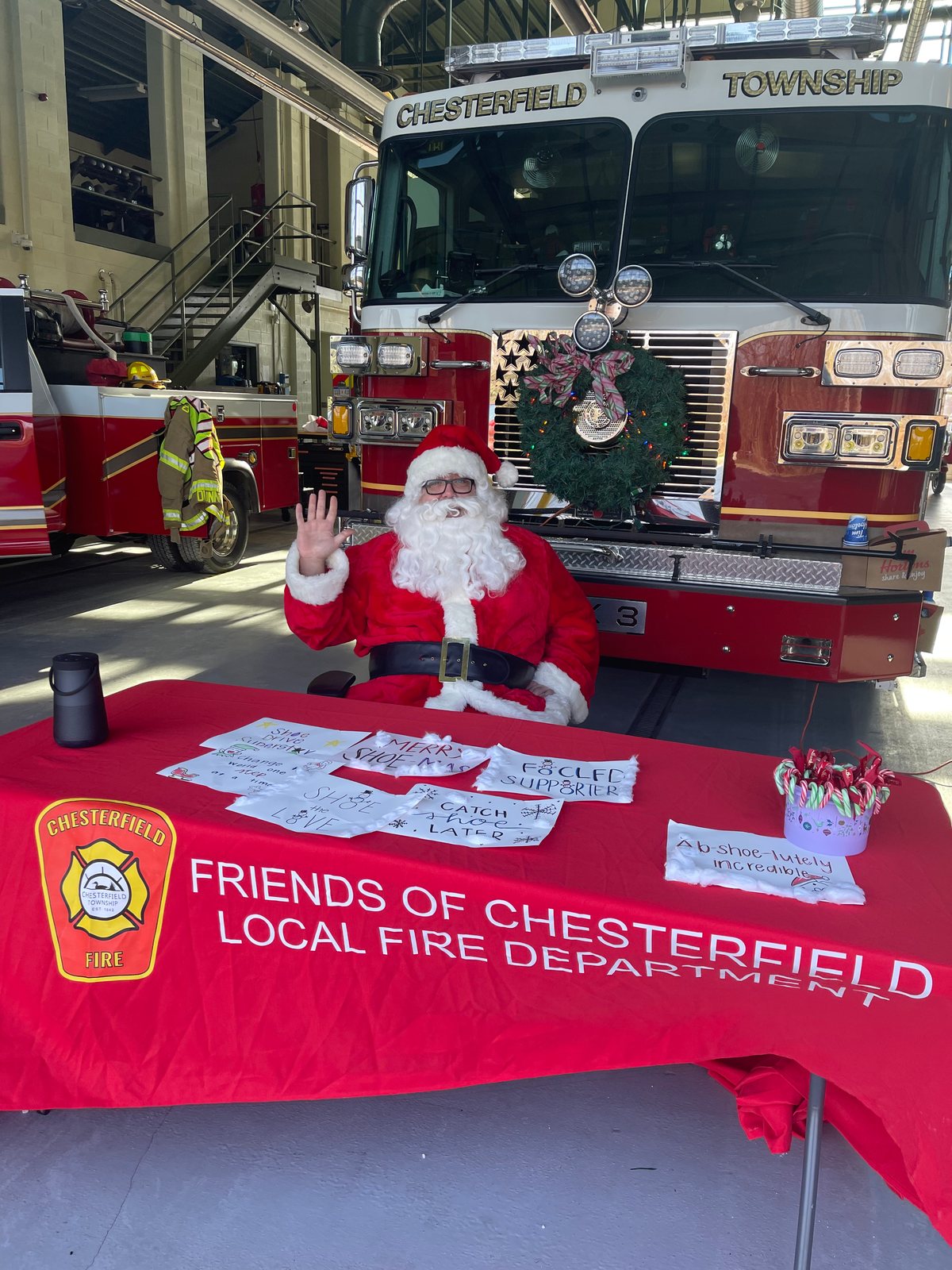 Santa at the Friends table in front of an engine at the December fill-a-fire-truck shoe drive