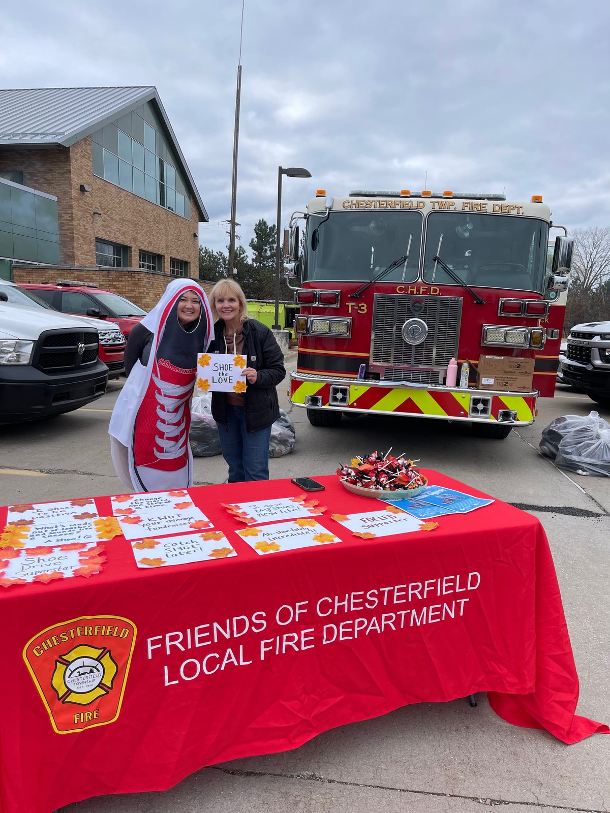 The Friends table at the fill-a-fire-truck shoe drive, with the shoe mascot and an engine