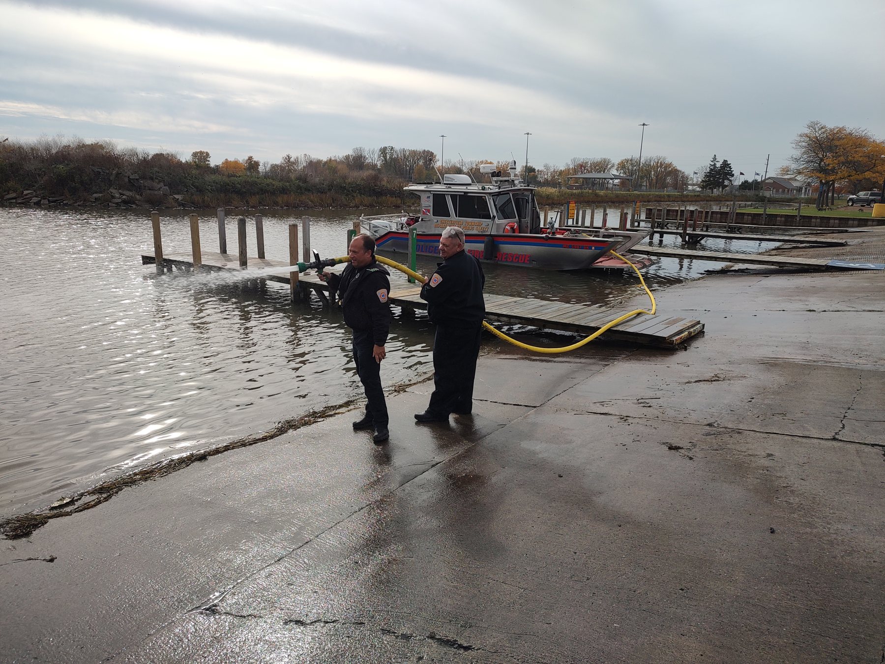 Crews working a hose line from the dock beside Marine 1