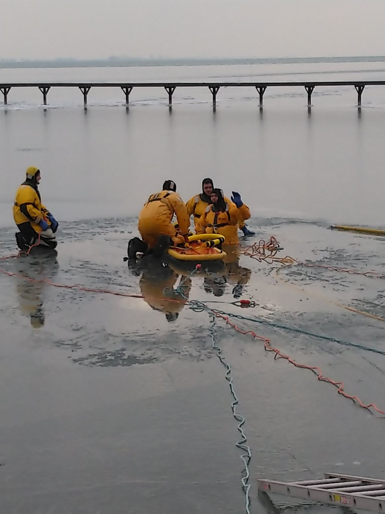 Ice rescue technicians working a victim at the edge of broken ice