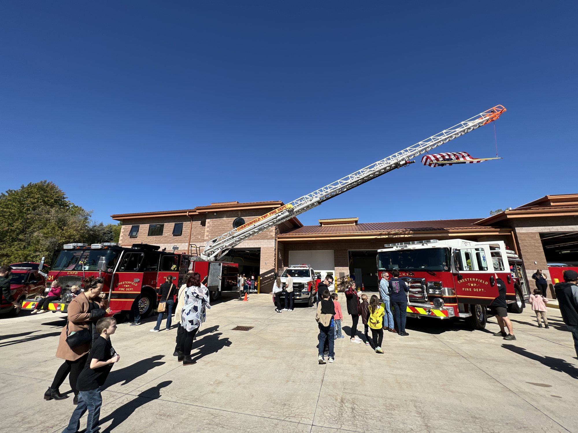 Families walking among Truck 3, the engines and a vintage pumper at the Open House