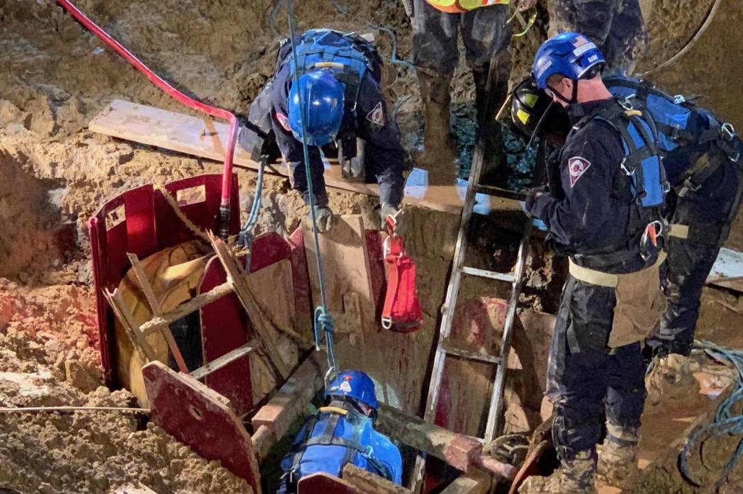 Technical rescue crews working in a trench with shoring and a ladder