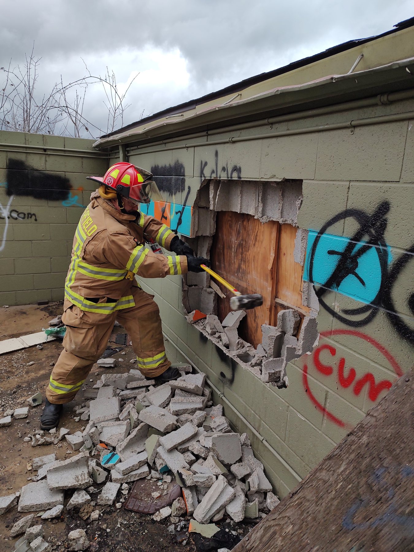 A firefighter breaching a block wall during forcible entry training