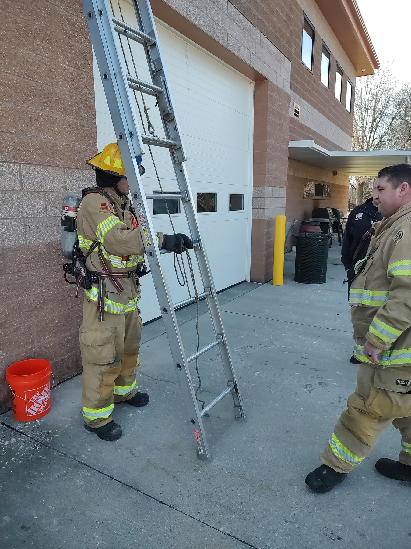 A firefighter in SCBA with a ground ladder at the station