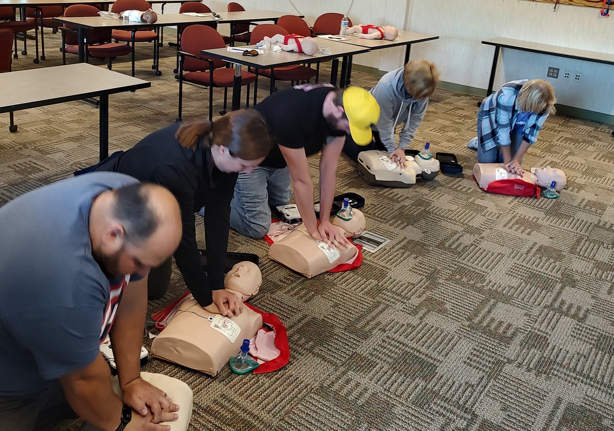 Residents practicing chest compressions on manikins during a CPR class at the fire station
