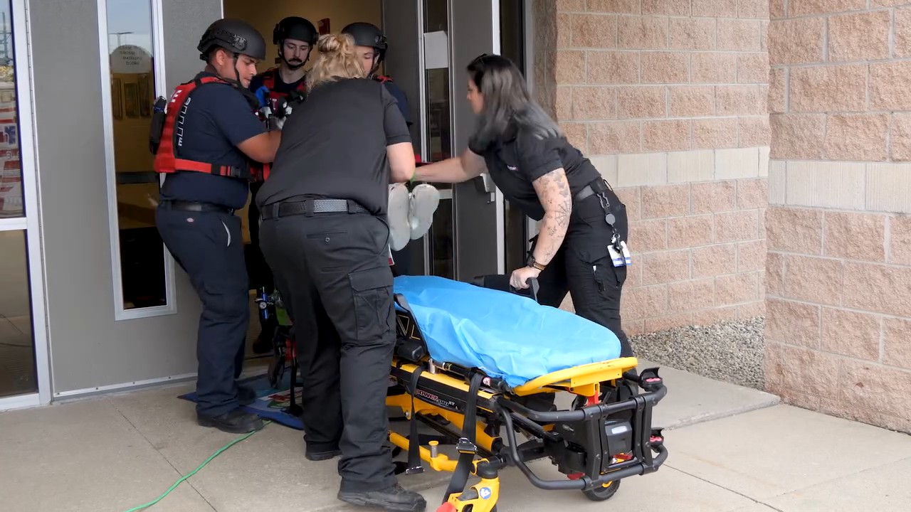 Rescue Task Force members and paramedics moving a patient to a stretcher during active shooter training
